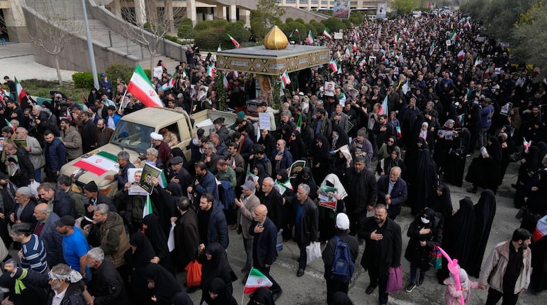 People follow a truck carrying the flag draped coffins of Gen. Ali Mohammad Naeini, a spokesperson for Iran’s paramilitary Revolutionary Guard and one of his comrades Amir Hossein Bidi , during their funeral procession in Tehran, Iran, Saturday, March 21, 2026. (AP Photo/Vahid Salemi)