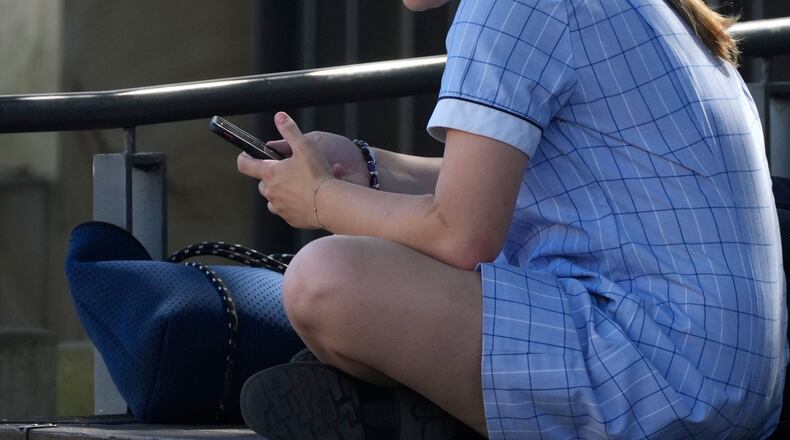 FILE - A young girl uses her phone while sitting on a bench in Sydney, Nov. 8, 2024. (AP Photo/Rick Rycroft, File)