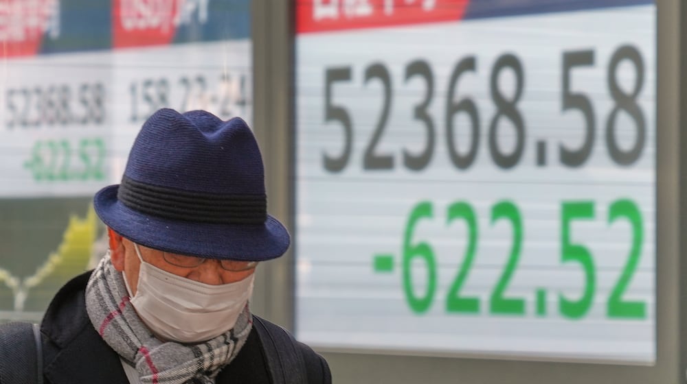 A person walks in front of an electronic stock board showing Japan's Nikkei index at a securities firm Wednesday, Jan. 21, 2026, in Tokyo. (AP Photo/Eugene Hoshiko)