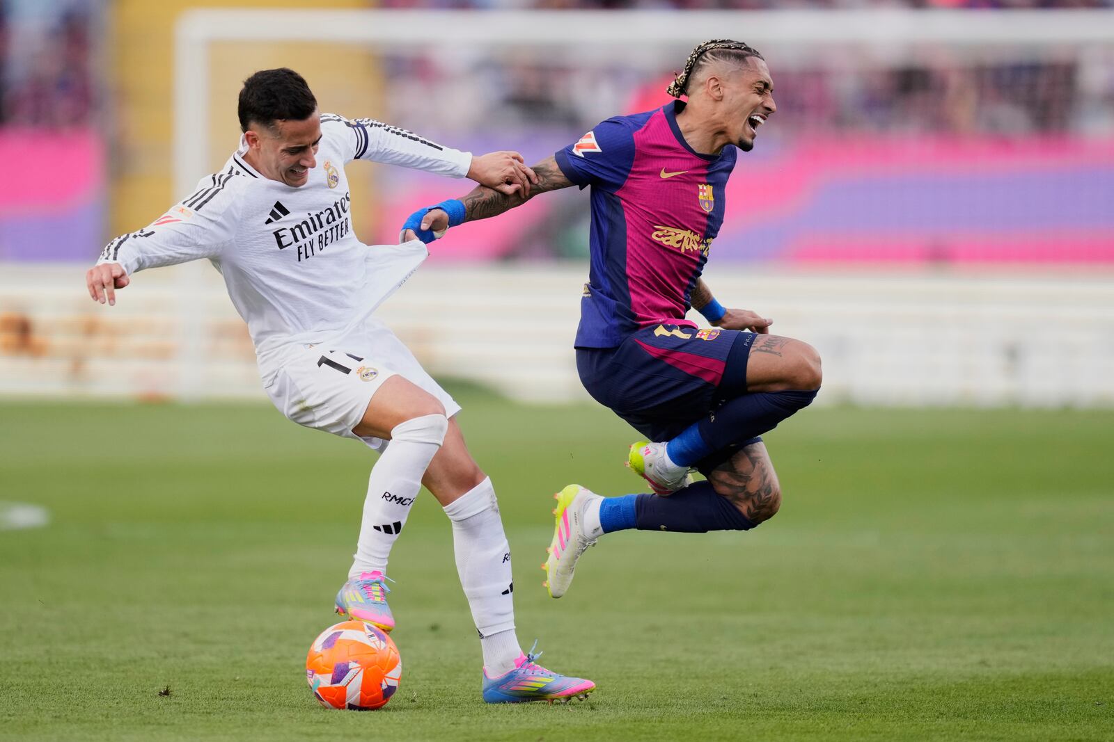 Barcelona's Raphinha, right, and Real Madrid's Lucas Vazquez fight for the ball during the Spanish La Liga soccer match between Barcelona and Real Madrid at the Lluis Companys Olympic Stadium in Barcelona, Spain, Sunday, May 11, 2025. (AP Photo/Jose Breton)