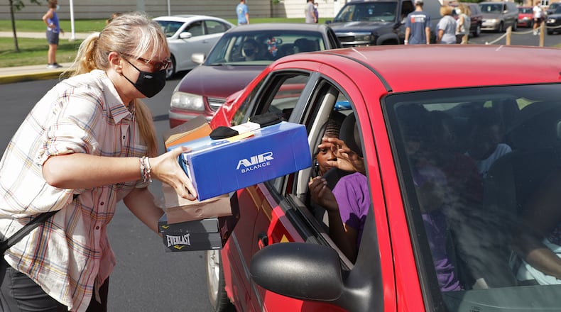 A Shoes 4 the Shoeless volunteer passes out shoes to the students in a car Monday during the drive-thru event at Springfield High School. BILL LACKEY/STAFF