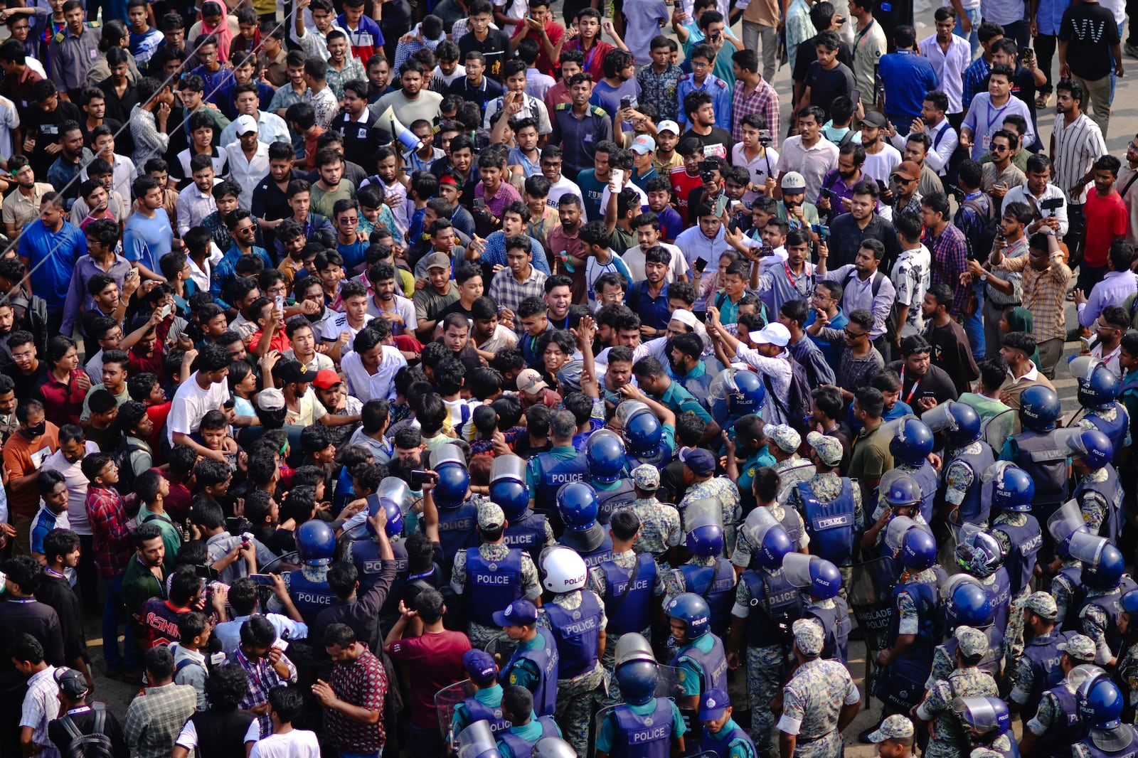Police officers stand guard as students shout slogans during a protest near the site of the crash of a Bangladesh air force training jet into a school, demanding accountability, compensation for victims' families and the halt of training flights, in Dhaka, Bangladesh, Tuesday, July 22, 2025. (AP Photo/Mahmud Hossain Opu)