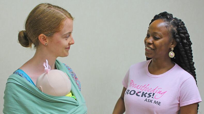 Clark County WIC program employees Erin Sanford and Safiyyah Truss demonstrate how to properly put on an infant wrap as part of Breastfeeding Awareness Month activities. JEFF GUERINI/STAFF