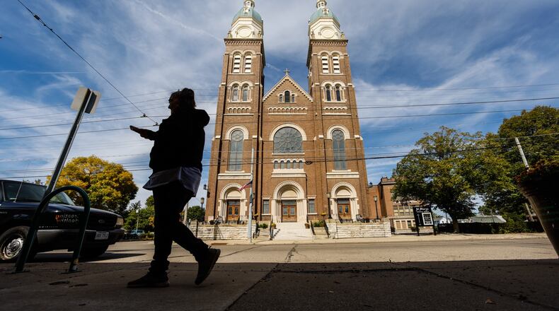 A person Thursday walks in front of St. Marys Catholic Church on Xenia Avenue. Citing pressures from a shrinking number of priests and declining membership, the Archdiocese of Cincinnati today released its draft plan to reorganize parishes across Southwestern Ohio.