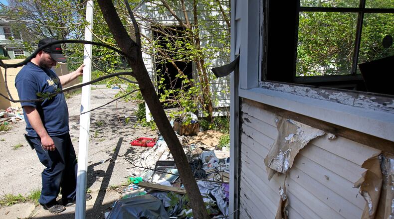 Tim Roth pulls a downspout out of tree branches next door to his shop, Neighbor's Automotive. 1208 Linden Avenue is an abandoned house that was stripped of aluminum and copper according to a Dayton police report taken on April 6. Ohio has the most insurance claims related to metal theft in the nation between 2010 and 2012. JIM WITMER / STAFF