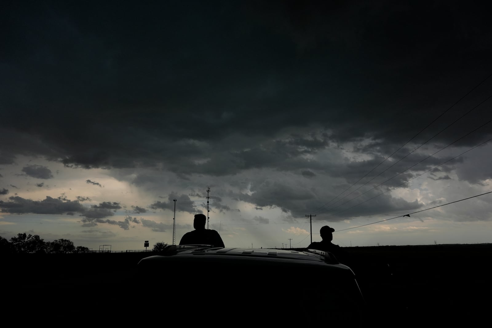 Victor Gensini, Northern Illinois University meteorology professor and a lead scientist of Project ICECHIP, right, and Logan Bundy, PhD Candidate at NIU and ICECHIP IOP assistant, left, stand at the command vehicle watching an approaching storm Tuesday, June 3, 2025, in Scotland, Texas. (AP Photo/Carolyn Kaster)
