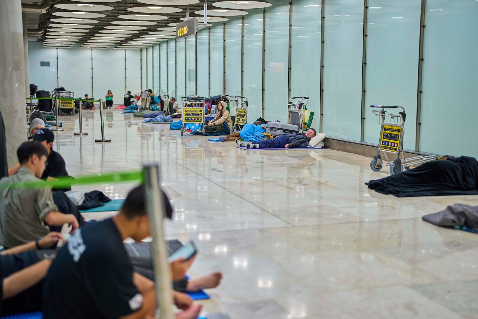 People sleep on the floor of Terminal 4 at Adolfo Suarez-Madrid Barajas Airport in Madrid, Spain, Thursday, May 15, 2025. (AP Photo/Manu Fernandez)
