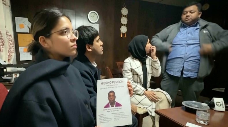 This image made from video provided by WKBW.COM shows a family friend holding a missing person flyer for Nurul Amin Shah Alam, while sitting with other family friends including Khaleda Shah, second from right, and MD Karim, far right, on Wednesday, Feb. 25, 2026, in Buffalo, N.Y. (WKBW.COM via AP)