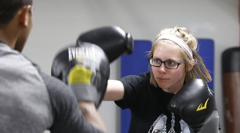 Tawney Hefner practices throwing punches with instructor Lucas Douthy in a kick boxing class at Springfield Health and Fitness. Bill Lackey/Staff
