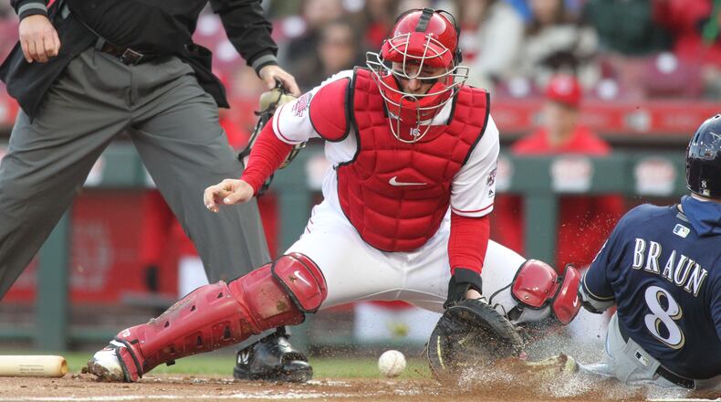 Reds catcher Tucker Barnhart fields a throw as Ryan Braun scores for the Brewers in the first inning on Monday, April 1, 2019, at Great American Ball Park in Cincinnati. David Jablonski/Staff