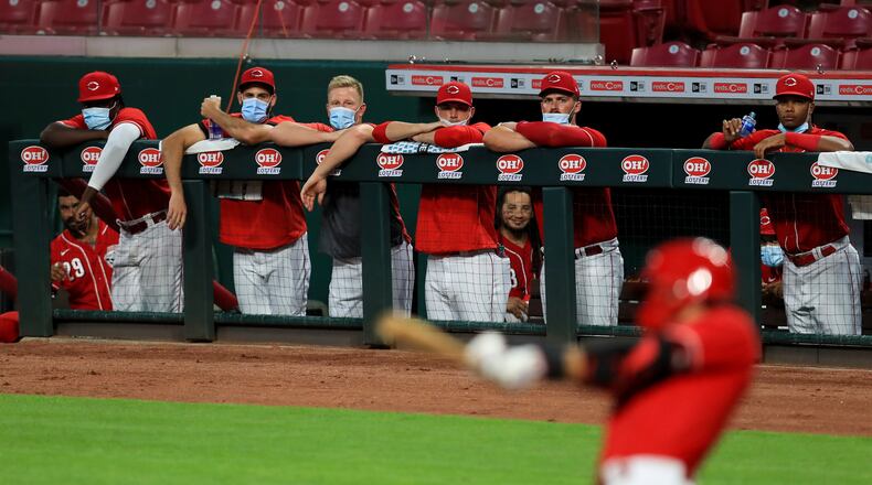 Members of the Cincinnati Reds wear masks as they watch the game from the dugout during an exhibition baseball game against the Detroit Tigers at Great American Ballpark in Cincinnati, Tuesday, July 21, 2020. The Reds won 9-7. (AP Photo/Aaron Doster)