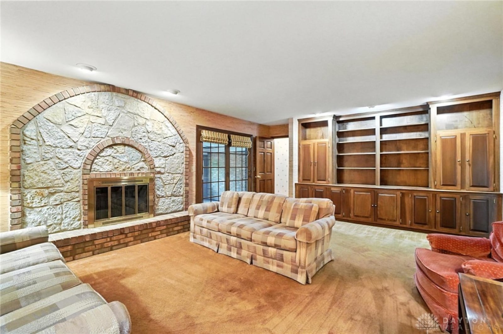This room is carpeted and has a unique brick and stone fireplace with recessed lighting above and a built in bookcase/hutch along one wall. CONTRIBUTED