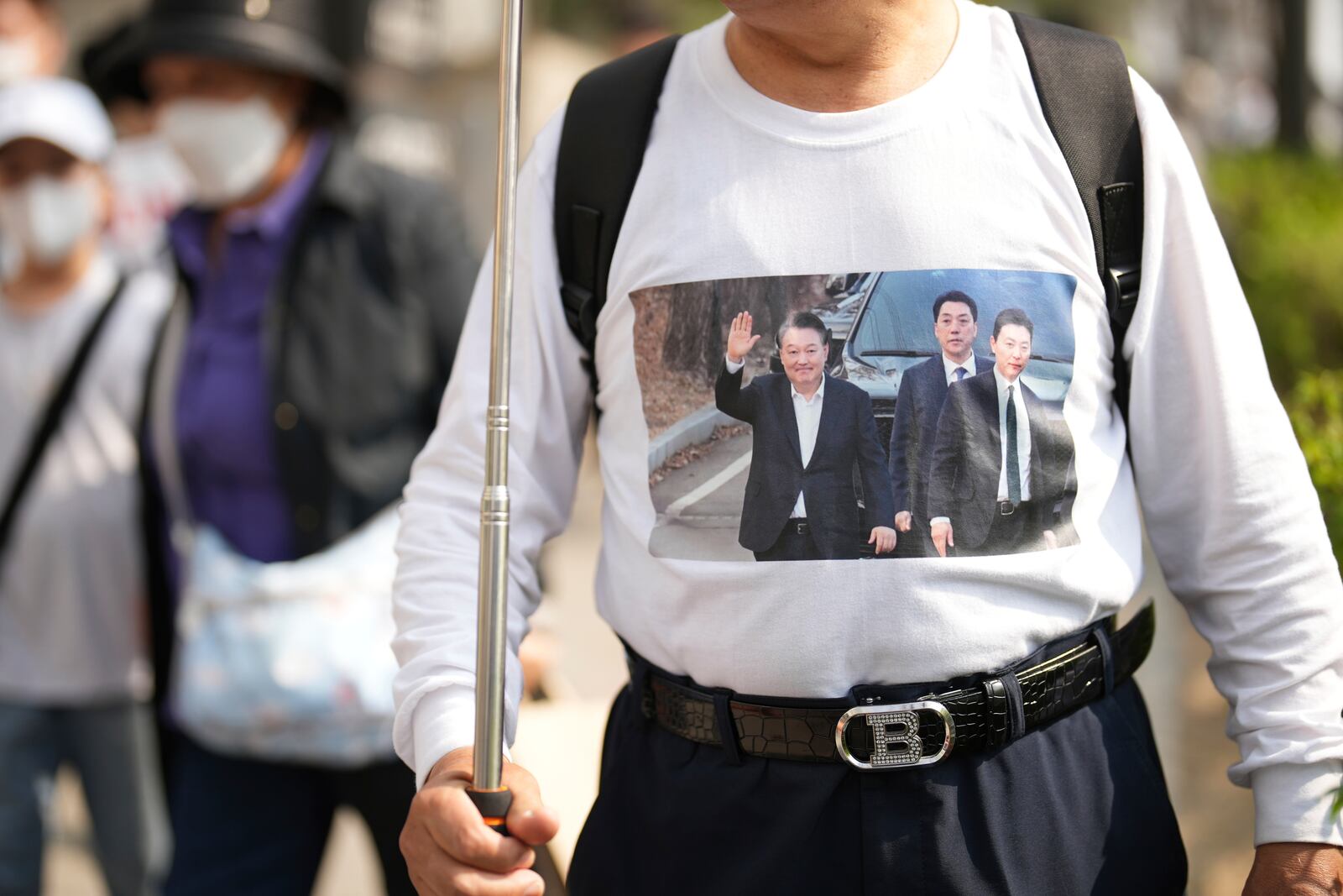 A supporter of recently removed South Korean President Yoon Suk Yeol wearing a dress with an image of Yoon stands near his private residence in Seoul, South Korea, Friday, April 11, 2025. (AP Photo/Lee Jin-man)