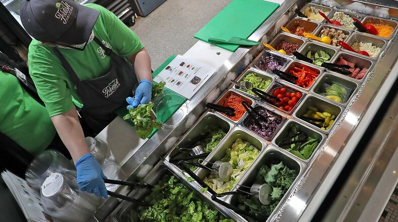 A Fresh Abilities associate builds a customer’s salad from a wide variety of fresh items Wednesday at COhatch. BILL LACKEY/STAFF
