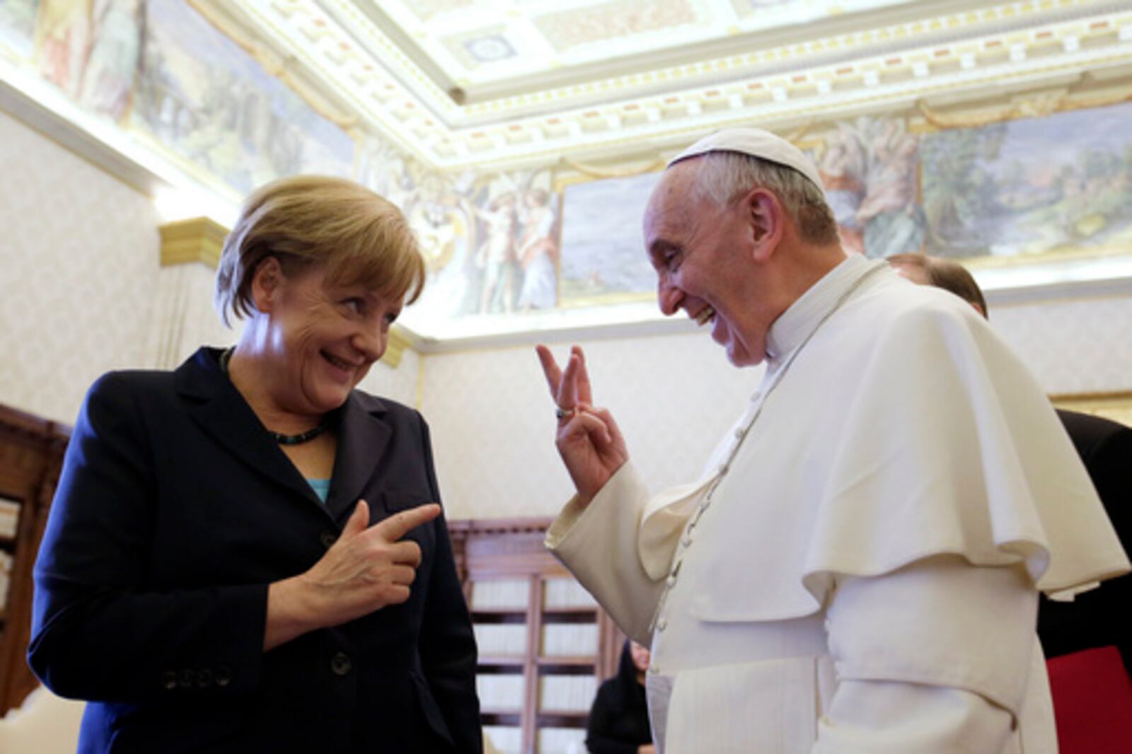 FILE - Pope Francis shares a light moment with German Chancellor Angela Merkel during their private audience at the Vatican, Saturday, May 18, 2013. (AP Photo/Gregorio Borgia, Pool, file)