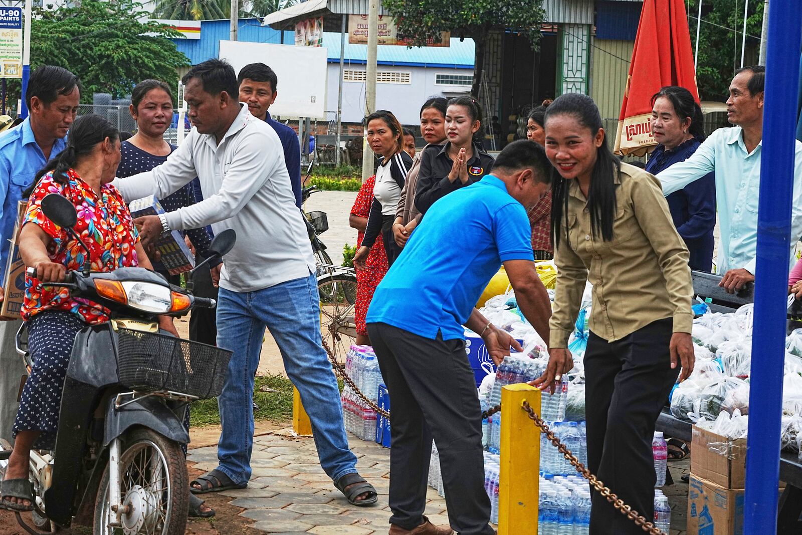 A Cambodian youth volunteer Chhar Sin, front right, welcomes villagers who donate their personal belongings for the displacing people at a sidewalk in Srey Snam district in Siem Reap province, Cambodia, Saturday, July 26, 2025, as border fighting between Thailand and Cambodia entered its third day, heightening fears of an extended conflict. (AP Photo/Heng Sinith)
