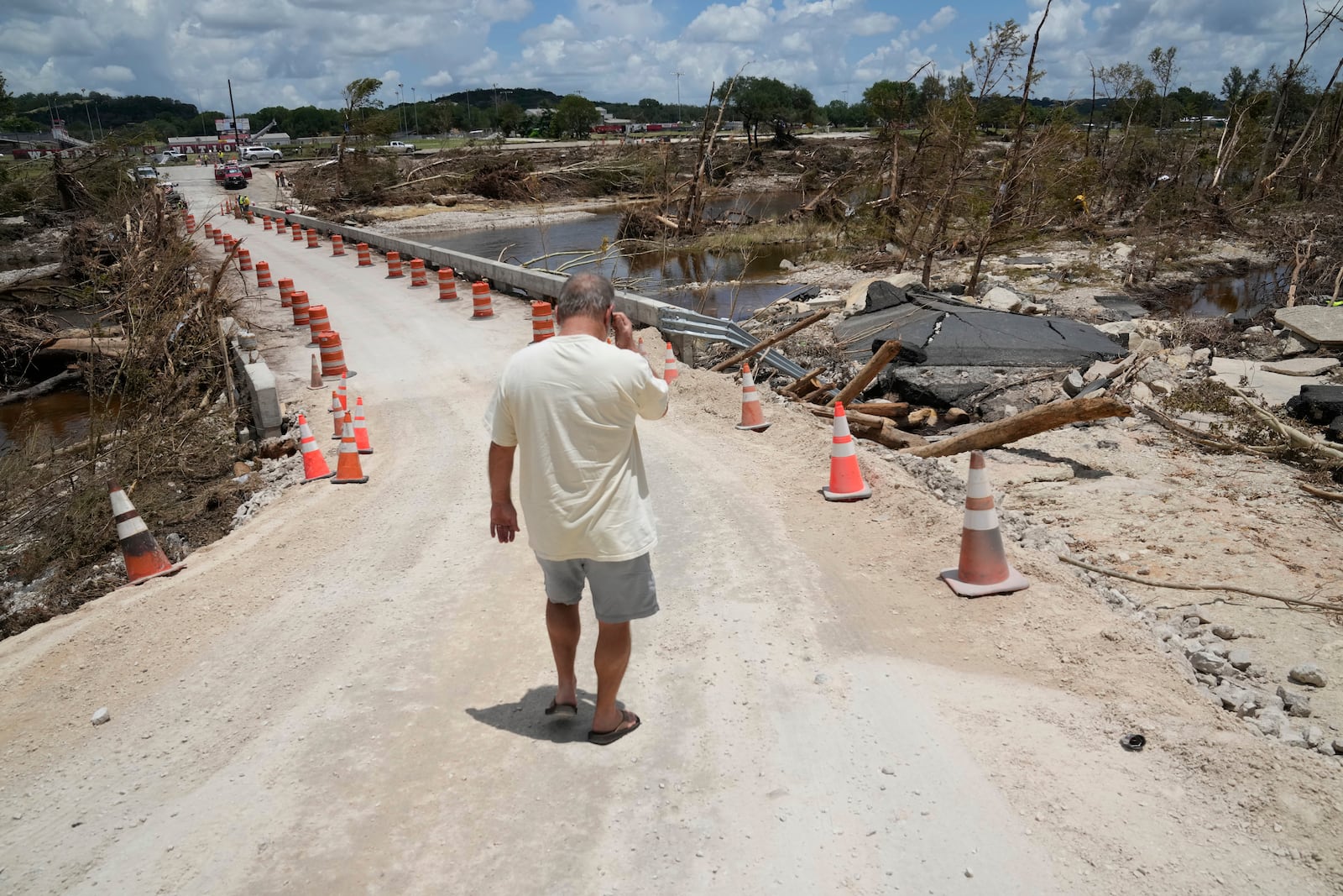 Resident Paul Snyder walks down the road to check out the condition of the bridge along the Guadalupe River after flooding in Kerrville, Texas on Wednesday , July 9, 2025. (AP Photo/Gerald Herbert)