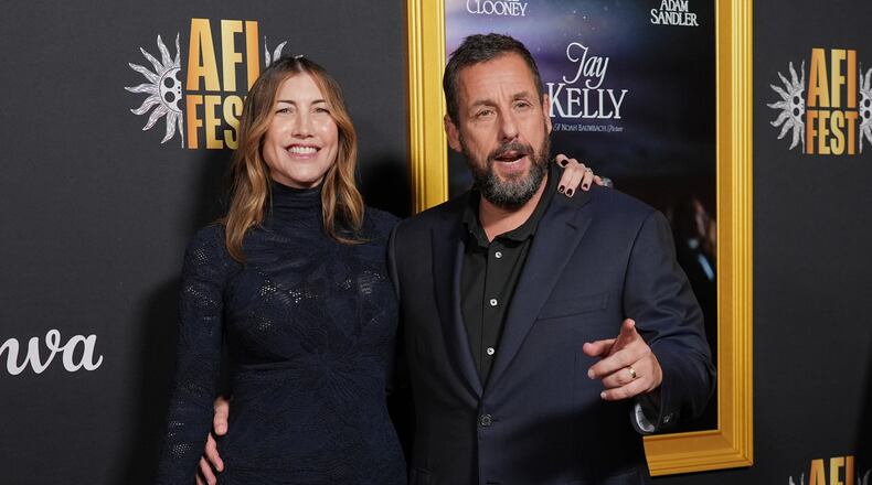 Adam Sandler, right, a cast member in "Jay Kelly," arrives with his wife Jackie Sandler at the AFI Fest premiere of the film on Thursday, Oct. 23, 2025, at TCL Chinese Theatre in Los Angeles. (AP Photo/Chris Pizzello)