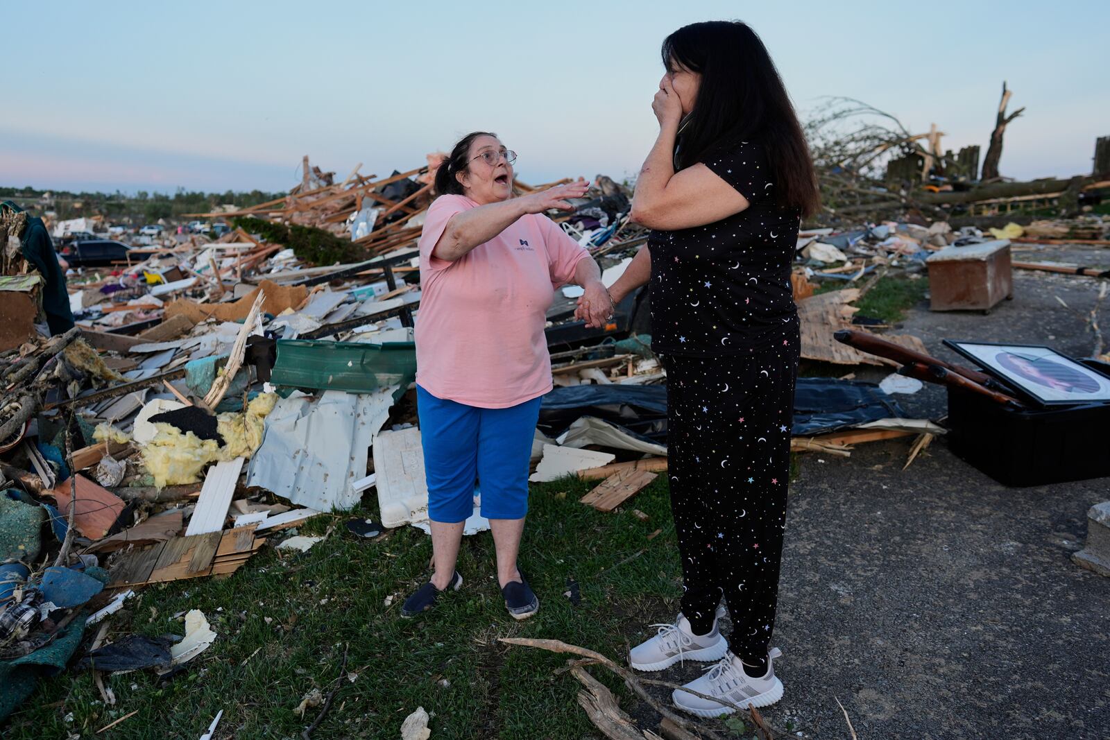 Bea Johnson, left, reaches for her sister Kristie Sexton, right, as she reacts standing next to her destroyed home after a severe storm passed through the area, Saturday, May 17, 2025, in London, Ky. (AP Photo/Carolyn Kaster)