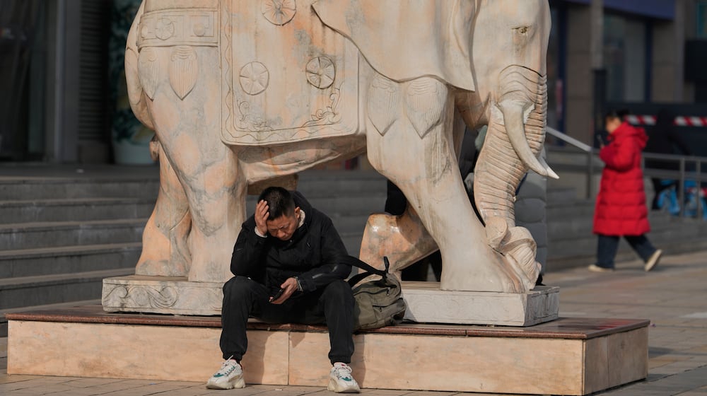 A man reacts while holding his smartphone in Beijing, China, Thursday, Jan. 15, 2026. (AP Photo/Ng Han Guan)