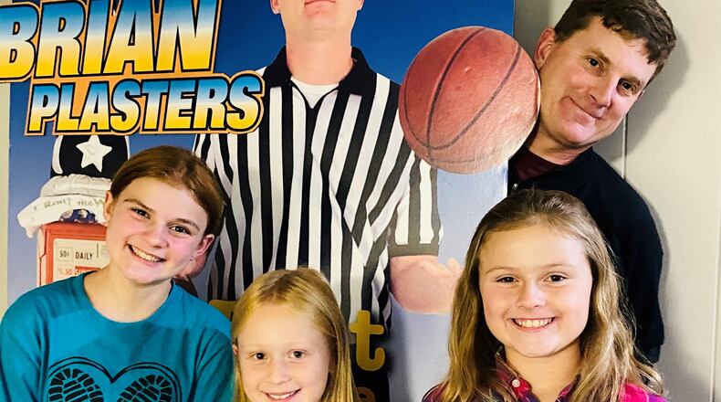 Brian Plasters stands with promotional cutout from his newspaper days along with his children, left to right, Kate, 12, Vera, 8, and Lucy,10. CONTRIBUTED