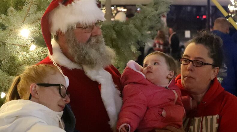 Santa poses for pictures in front of the Springfield Holiday Tree during the Grand Illumination Friday. BILL LACKEY/STAFF