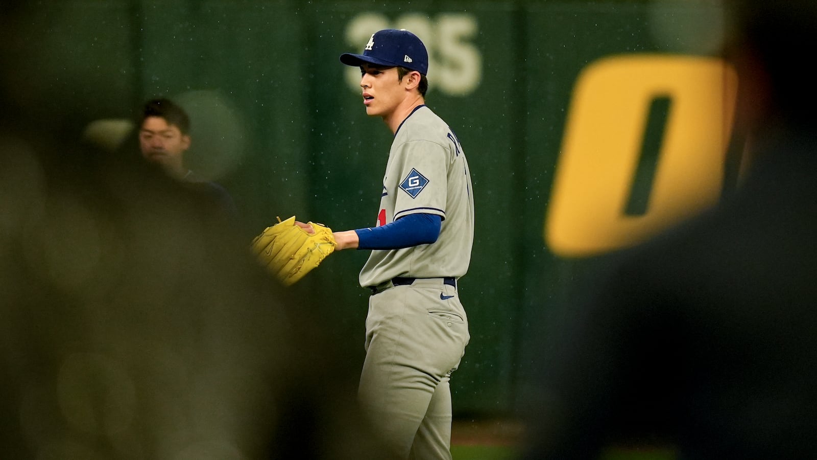 Los Angeles Dodgers pitcher Roki Sasaki warms up in the rain as ground crew removes the tarp ahead of a baseball game between the Atlanta Braves and the Los Angeles Dodgers, Saturday, May 3, 2025, in Atlanta. (AP Photo/Mike Stewart)