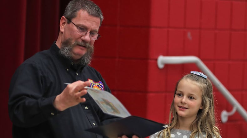 Piper Burcham, a third grader at Snowhill Elementary, is presented with an award by Charles Arnold, from the State Marshall’s Office, for her fire awareness poster she made for their annual contest. Piper is one of 12 students in the state to receive an award for her poster. BILL LACKEY/STAFF