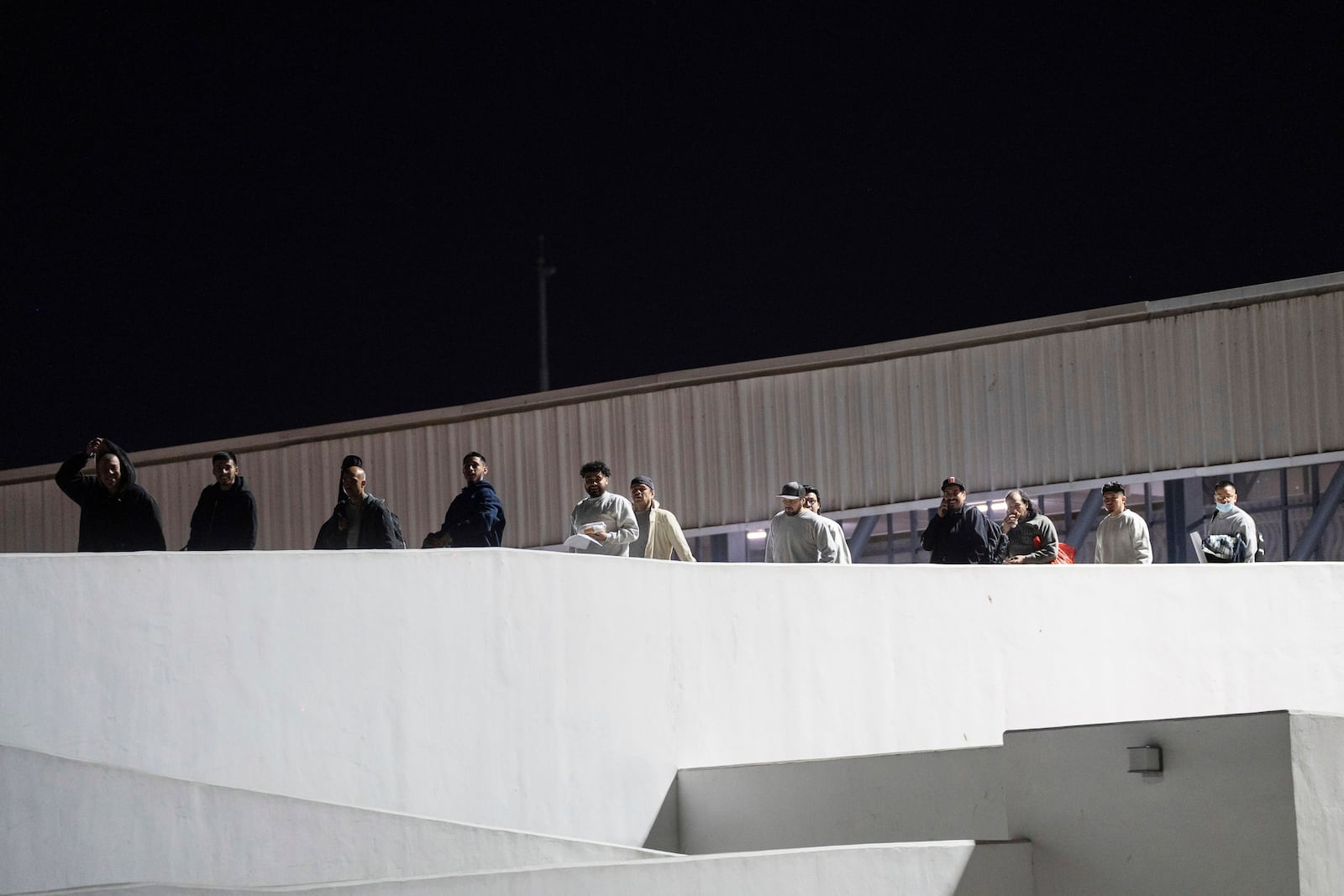 FILE - Migrants walk into Mexico after being deported from the U.S., at El Chaparral pedestrian border bridge in Tijuana, Mexico, Jan. 21, 2025. (AP Photo/Felix Marquez, File)