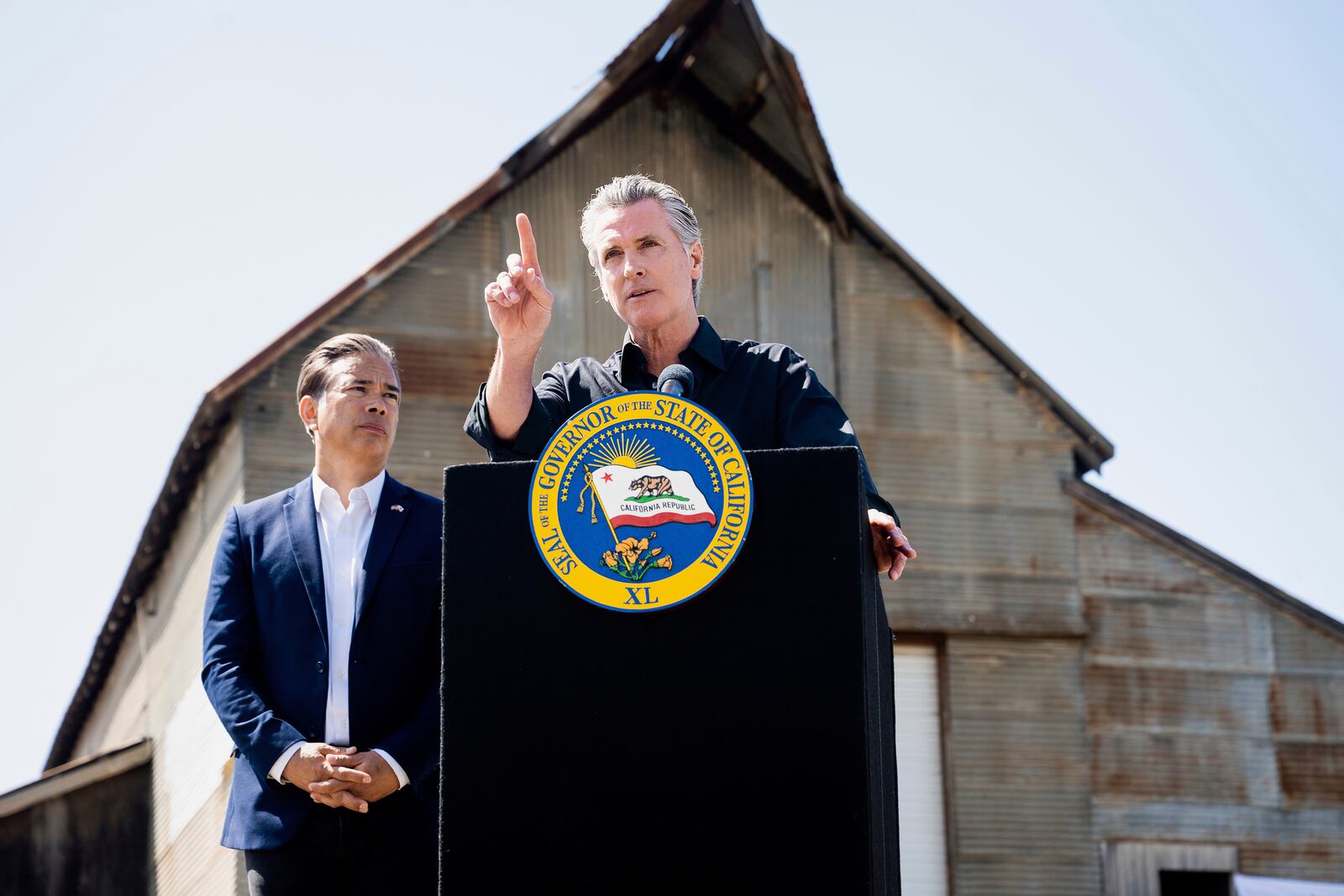 California Gov. Gavin Newsom discusses President Donald Trump's tariffs, as California Attorney General Rob Bonta, left, listens, during a press conference on Wednesday, April 16, 2025, at an almond farm in Ceres, Calif. (AP Photo/Noah Berger)