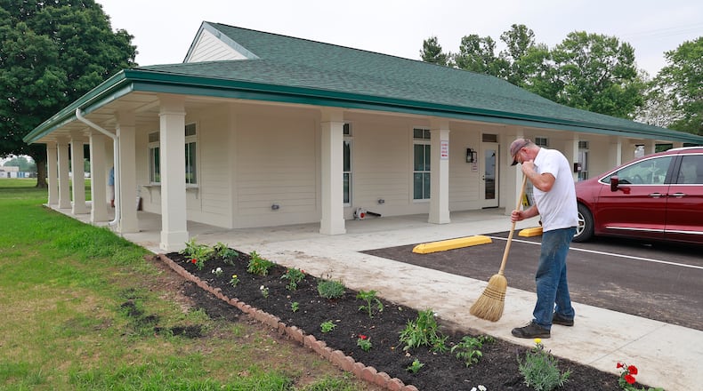 David Ray sweeps dirt off the sidewalk after planting flowers in front of the new Clark County Fair Office Monday, June 19, 2023. BILL LACKEY/STAFF