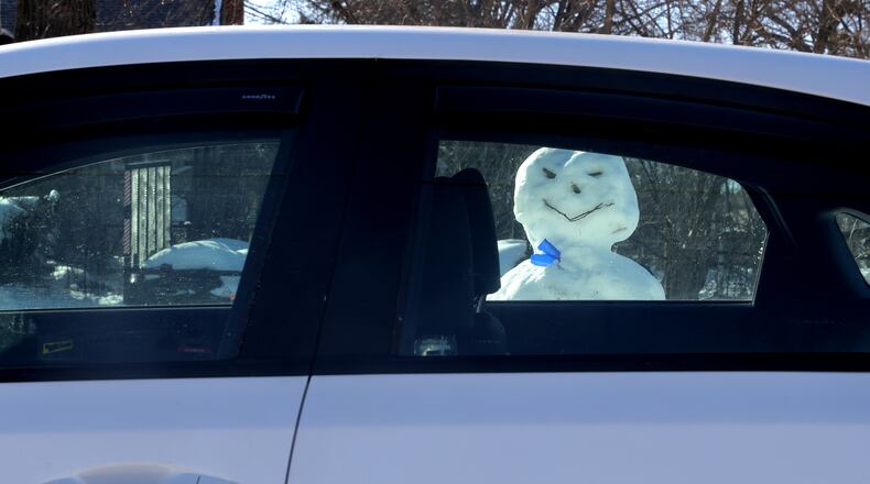 A snowman, with a devious smile, seems to be looking through a car's passenger window Monday, Jan. 13, 2025 along North Street in Springfield. BILL LACKEY/STAFF