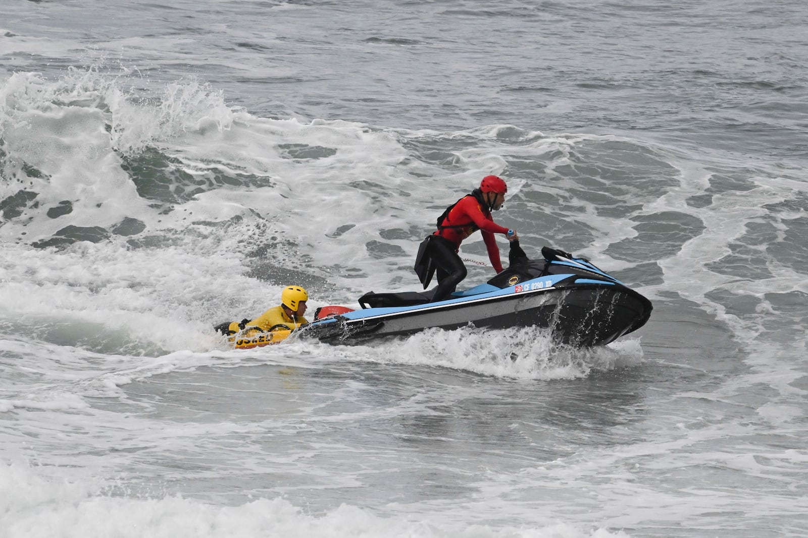 Lifeguards look for survivors after a boat capsized in the surf Friday, May. 5, 2025, in at Torrey Pines State beach in San Diego, Calif. (AP Photo/Denis Poroy)