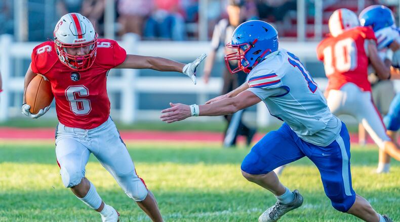 Southeastern High School sophomore Braxton Harrington runs past Northwestern High School junior Mason McDermott during their game at Southeastern on Friday, Aug. 22 at Trojan Stadium in South Charleston. The Warriors won 50-7. RODNEY GETZ / CONTRIBUTED PHOTO RODNEY GETZ / CONTRIBUTED PHOTO