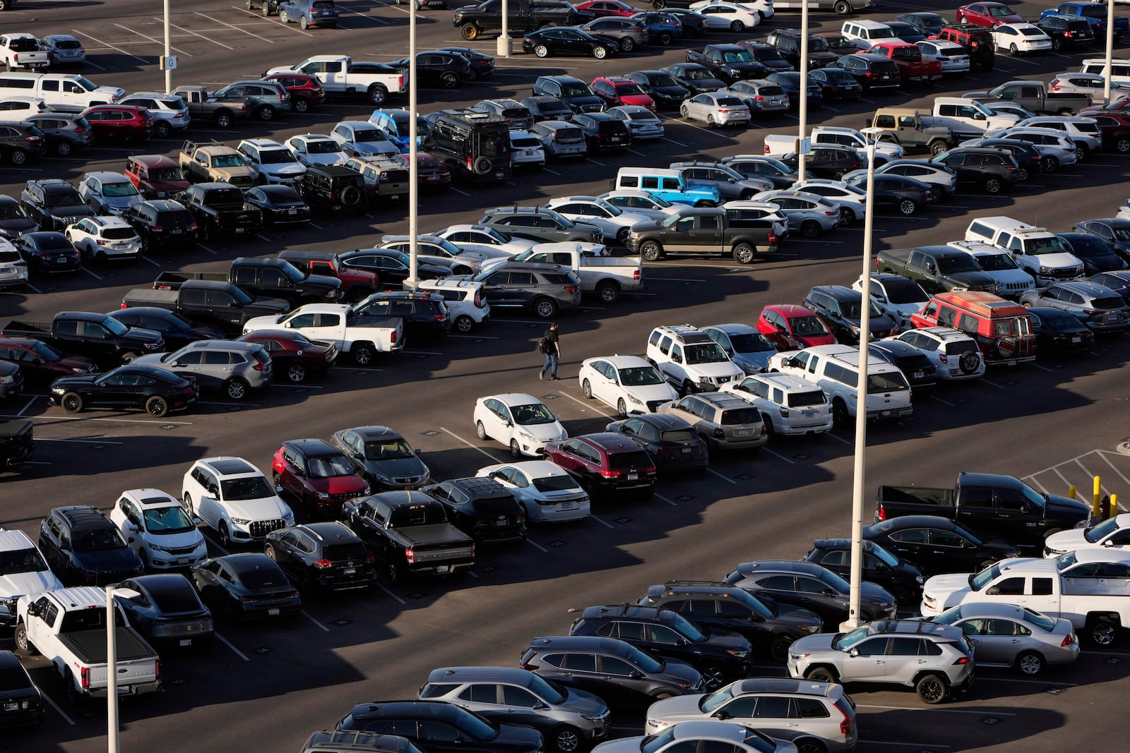 FILE - A person walks through a parking lot at Harry Reid International Airport, Wednesday, April 9, 2025, in Las Vegas. (AP Photo/John Locher, File)