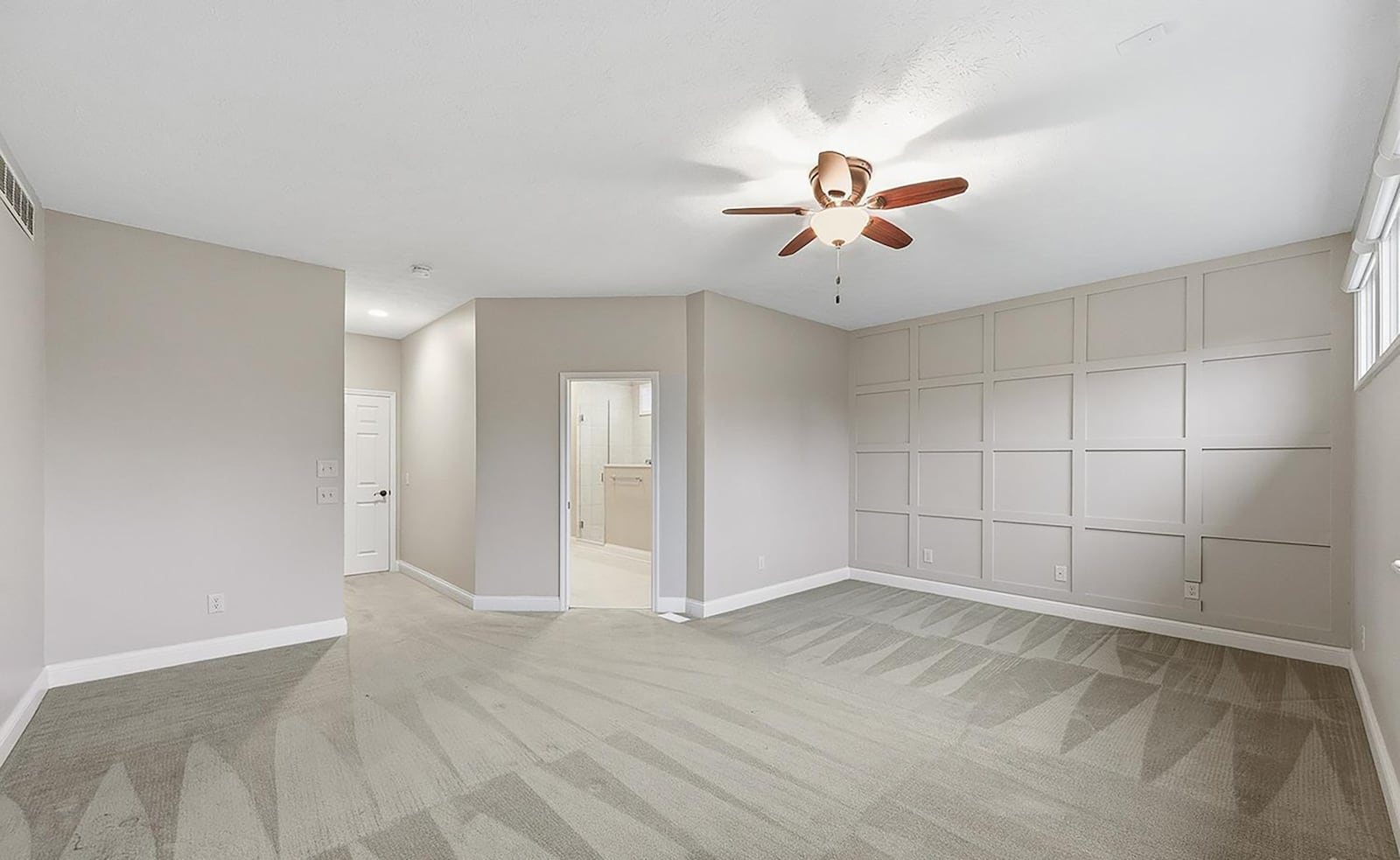 The first floor primary suite has neutral carpeting, a ceiling fan, a walk in closet and ensuite bathroom with oversized walk in shower. CONTRIBUTED