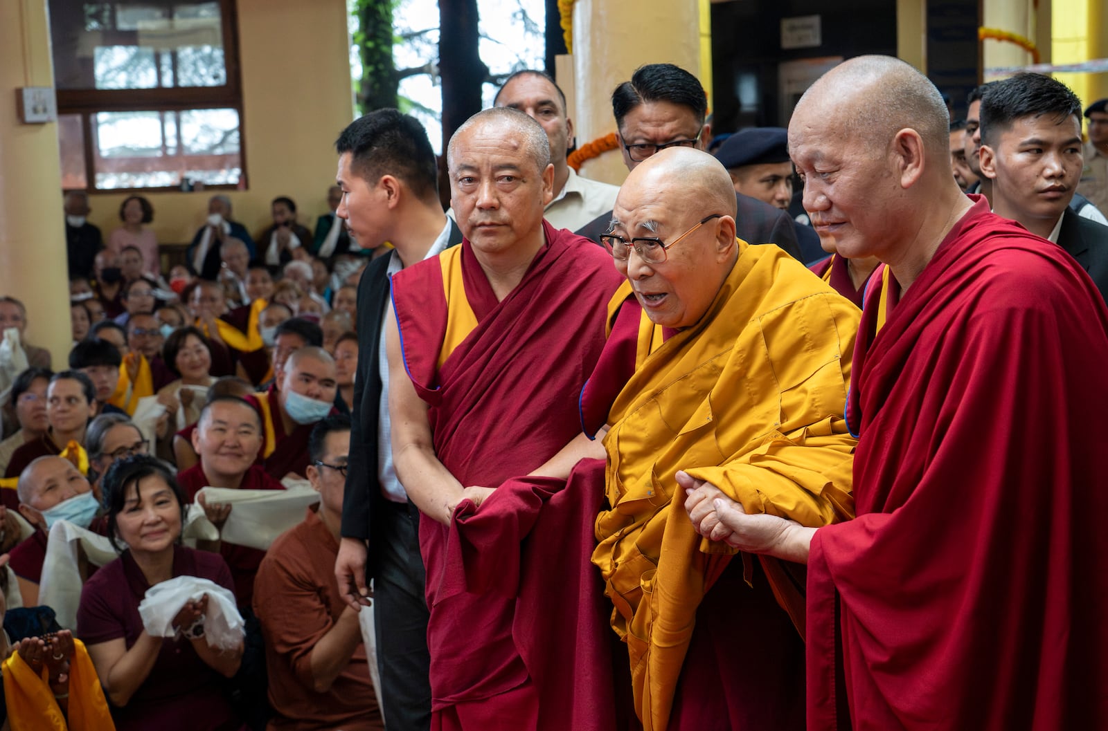 Tibetan spiritual leader the Dalai Lama, in yellow robe, is helped by attendant monks as he arrives to preside over an event during which Tibetan exiles prayed for his longevity, a day before his 90th birthday, in Dharamshala, India, Saturday, July 5, 2025.(AP Photo/Ashwini Bhatia)