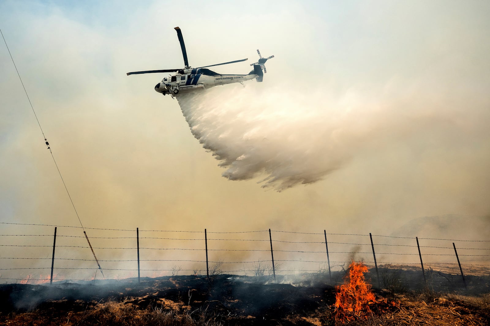 A helicopter drops water on the Madre Fire as it burns along Highway 166 on Thursday, July 3, 2025, in San Luis Obispo County, Calif. (AP Photo/Noah Berger)