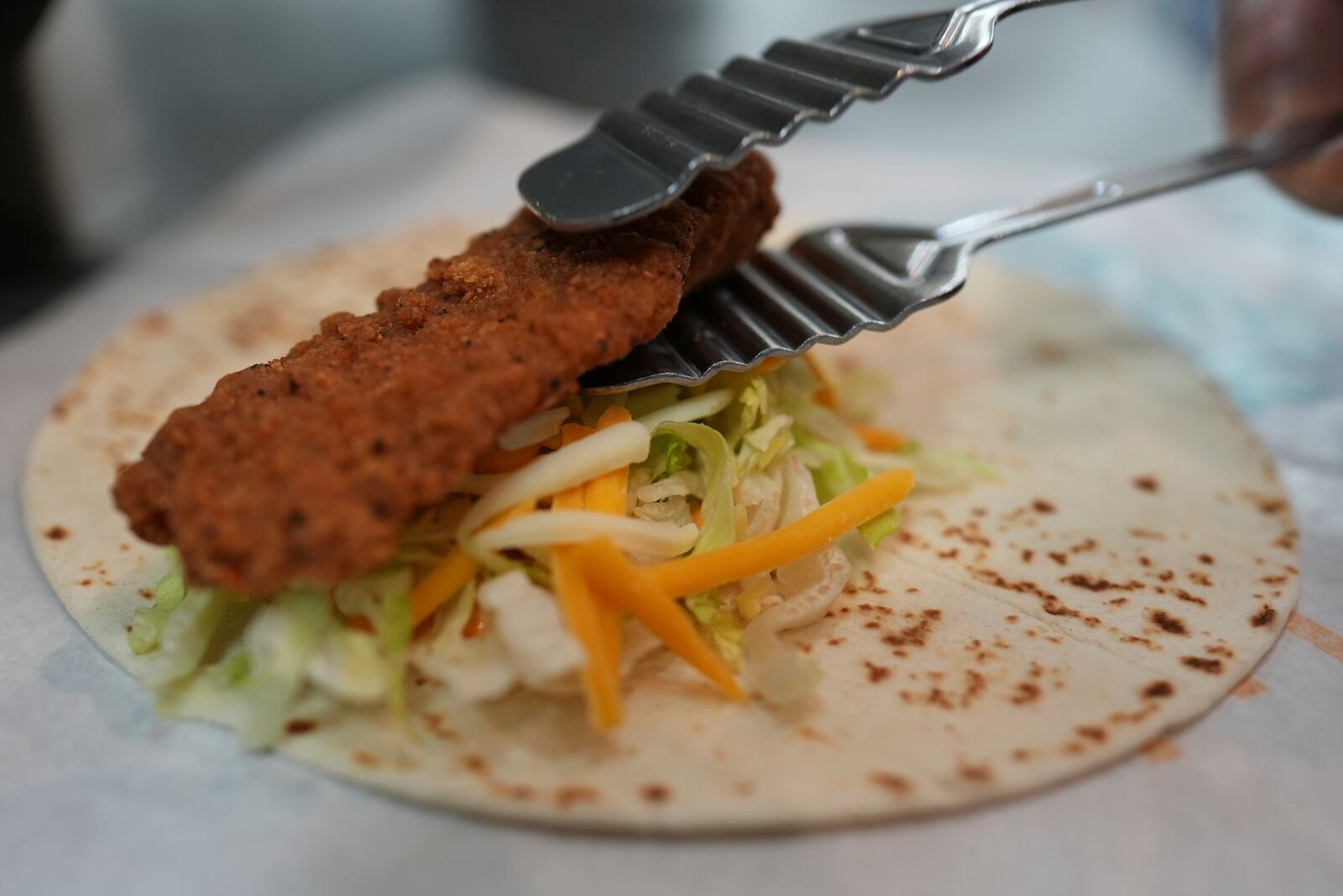 Charles L. Krumsiek, a McDonald's chef, puts a chicken on a tortilla to make a snack wrap at McDonald's Headquarter in Chicago, Thursday, May 29, 2025. (AP Photo/Nam Y. Huh)