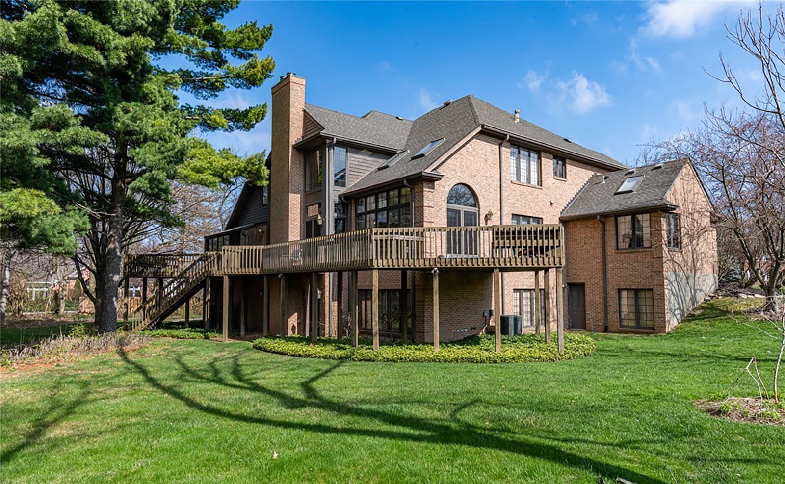 the rear of the home feature a wood deck with railings that extends the entire length of the home and overlooks the wooded lot.