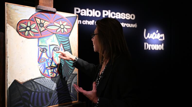 Art expert Agnes Sevestre-Barbe points to a rediscovered Picasso painting "Bust of a Woman in a Flowery Hat", Wednesday, Oct. 22, 2025 in Paris. The portrait painted in 1943 will be sold at auction Friday in Paris, was bought in 1944 and shows his partner Dora Maar. (AP Photo/Emma Da Silva)