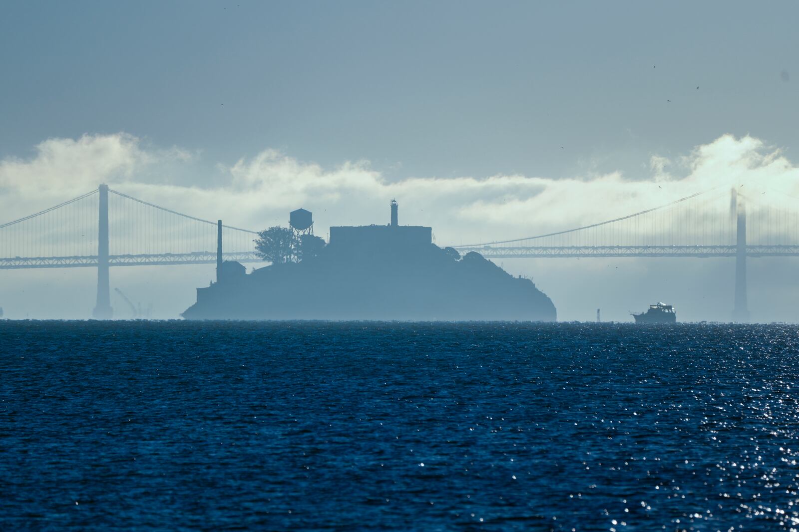 FILE - A boat makes its way toward Alcatraz Island with the San Francisco-Oakland Bay Bridge in the background in this view from Sausalito, Calif., Dec. 13, 2023. (AP Photo/Eric Risberg, File)