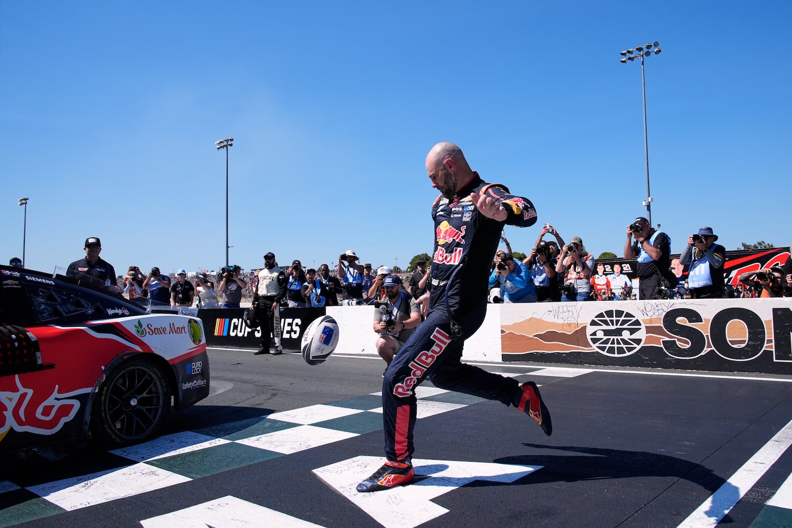 Shane van Gisbergen kicks a rugby ball as he celebrates after winning a NASCAR Cup Series auto race at Sonoma Raceway, Sunday, July 13, 2025, in Sonoma, Calif. (AP Photo/Godofredo A. Vásquez)