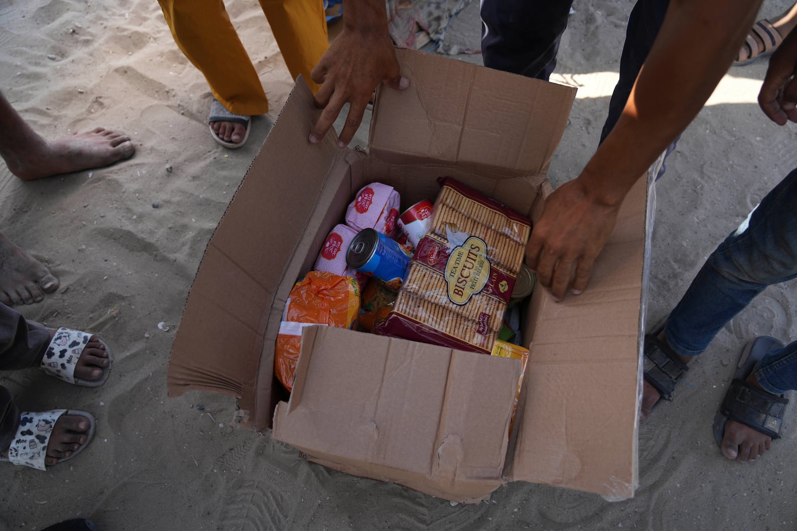 Palestinians open a box containing food and humanitarian aid packages delivered by the Gaza Humanitarian Foundation, a U.S.-backed organization approved by Israel, in Rafah, southern Gaza Strip, on Tuesday, May 27, 2025. (AP Photo/Abdel Kareem Hana)