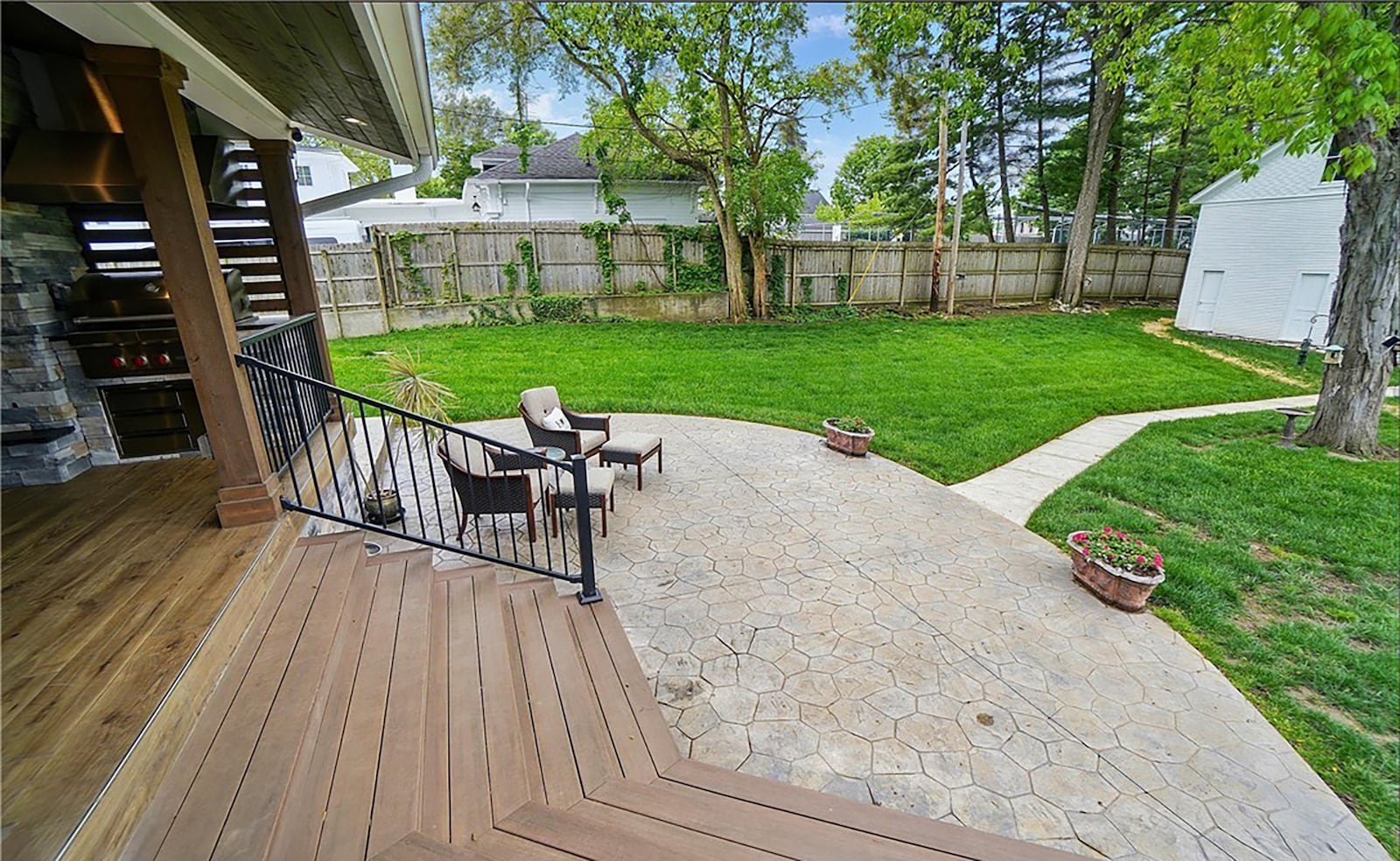 The back of the home features an updated covered deck with outdoor kitchen. The original carriage house has a concrete walkway leading from patio.