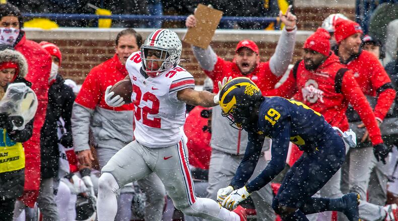 Ohio State running back TreVeyon Henderson (32) tries to fend off Michigan defensive back Rod Moore (19) in the first quarter of an NCAA college football game in Ann Arbor, Mich., Saturday, Nov. 27, 2021. (AP Photo/Tony Ding)