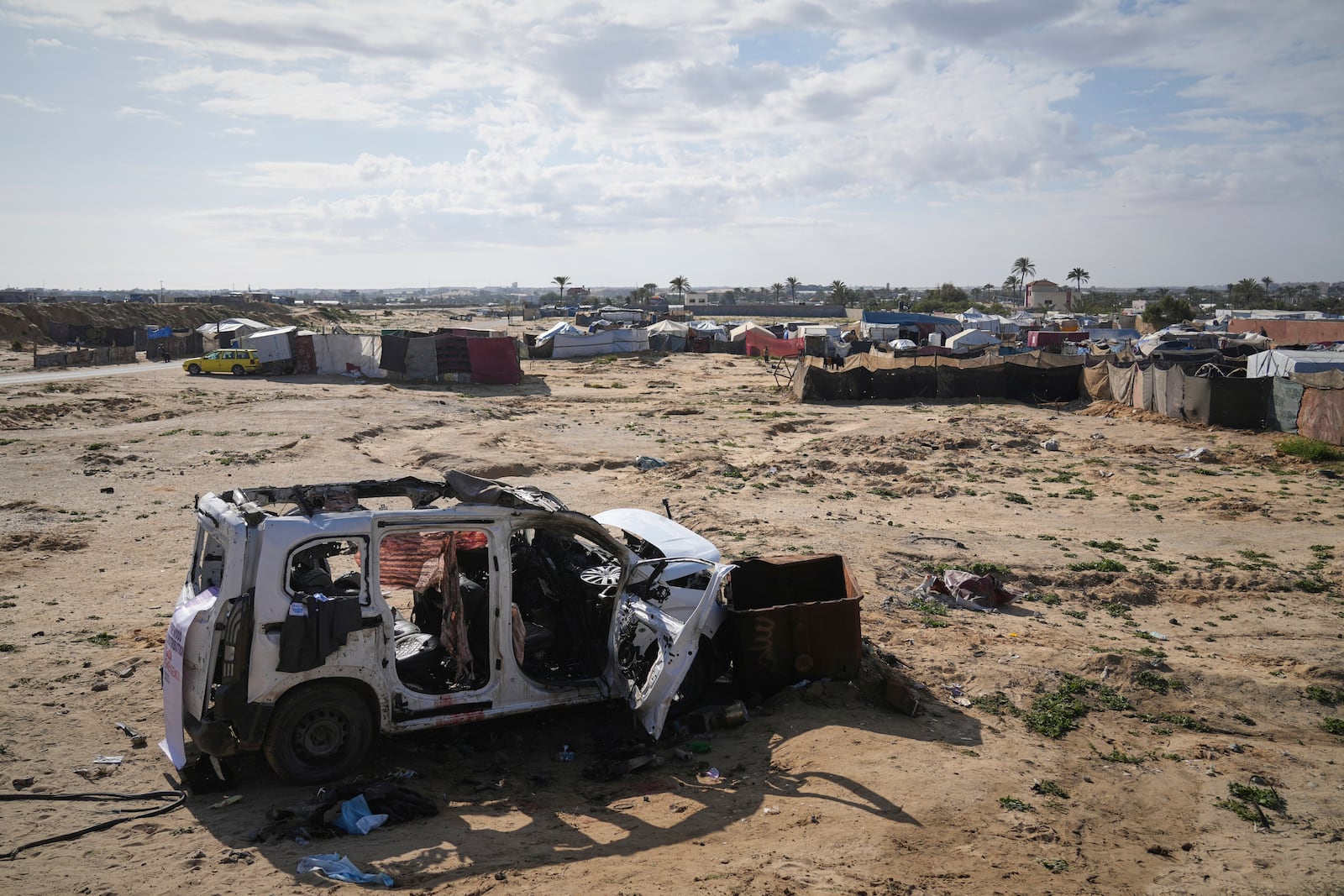 The wreckage of a car struck earlier by an Israeli army attack that killed at least seven people, six of them the Abu Mahadi brothers, sits on the outskirts of Deir al-Balah, in the central Gaza Strip, Sunday, April 13, 2025. (AP Photo/Abdel Kareem Hana)