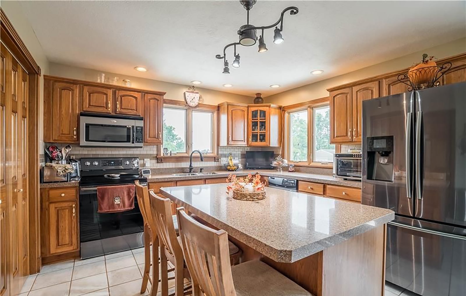 The kitchen has tile flooring, wood cabinets, recessed lighting and an island with bar seating. CONTRIBUTED