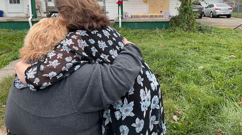 Debby Seymour and Teresa Petersen, loved ones of Gloria Dickinson, embrace in front of the house where Dickinson was found during a vigil on North Douglas Avenue on Monday evening.