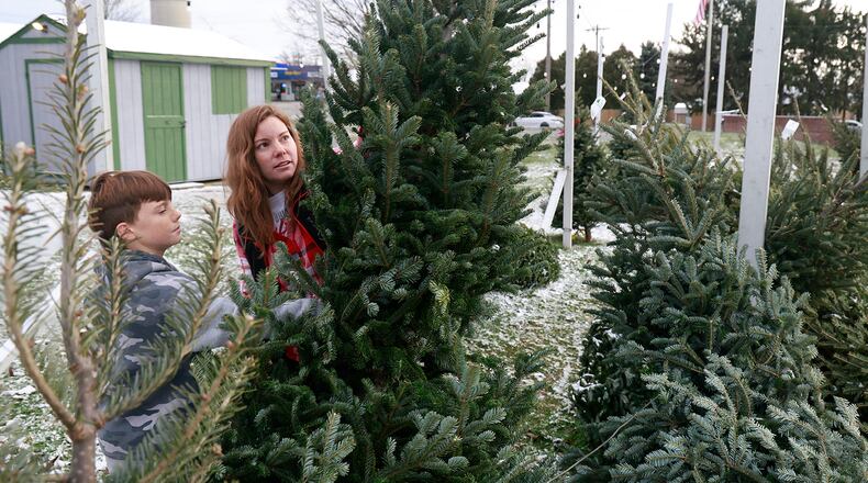 Kandis Hufford and her son, Colton, pick out a Christmas tree at the Northridge Lions Club tree lot at the intersection of Moorefield Road and Ridgewood Road West Wednesday, Dec. 11, 2024. According to a sign on site, this is the 67th year that the Lions Club has sold Christmas Trees. BILL LACKEY/STAFF